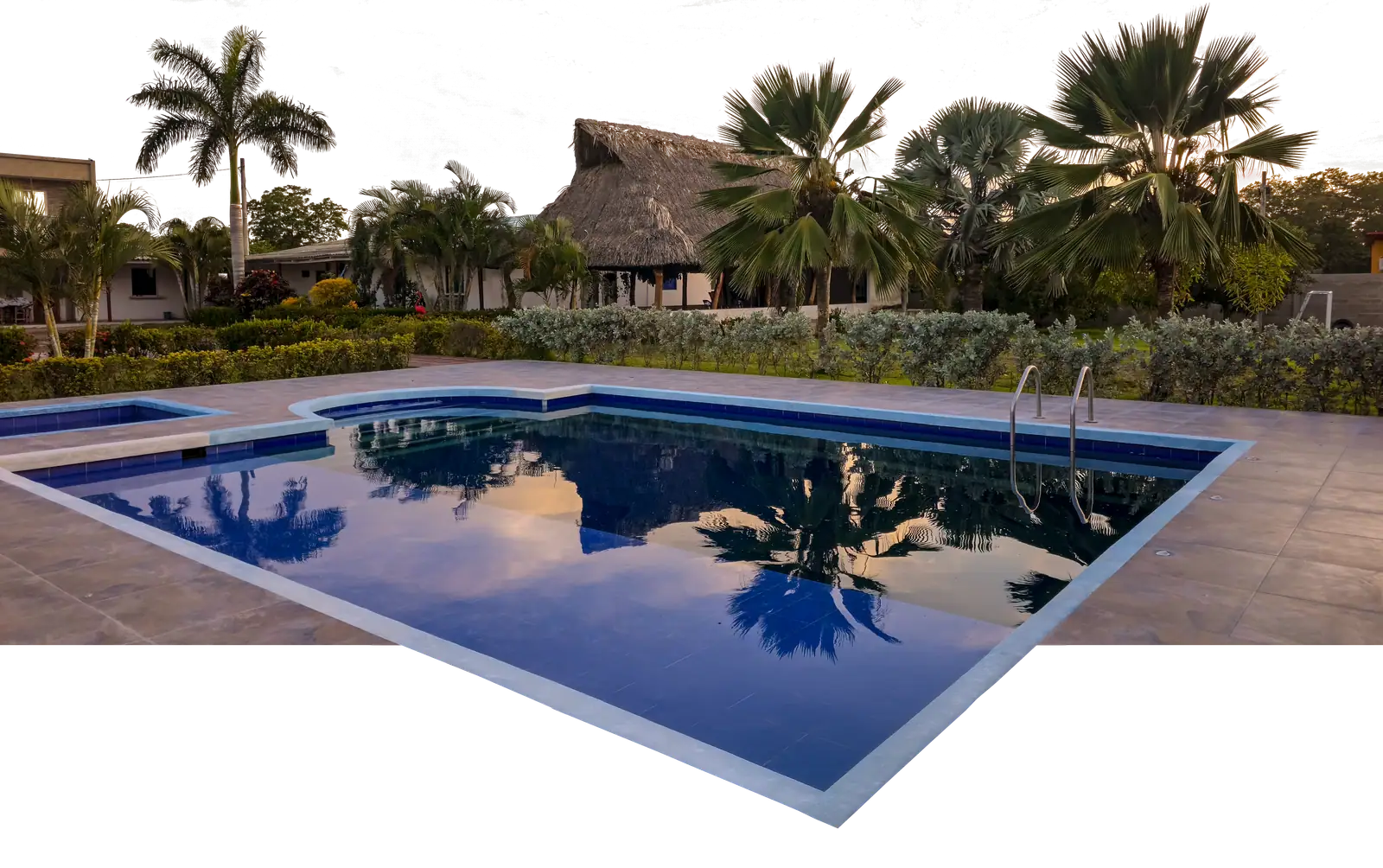 Piscina, bohío y palmas de la comunidad terapéutica al atardecer